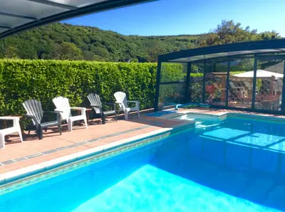 a swimming pool with chairs and a table next to at WE ARE UNIQUE ! 4 min walk to Beach, Pubs, Restaurants, Shops, Htd Pool, Hottub, Games rm, 1 acre Garden, BBQ's Coast to Coast cycle path, Beautiful, Bassets acre, Only six 1-3 bedroom SUPERB apartments, Free Parking and WIFI in Portreath