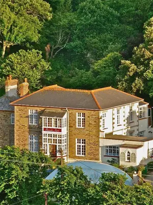 a large brick house in front of a mountain at WE ARE UNIQUE ! 4 min walk to Beach, Pubs, Restaurants, Shops, Htd Pool, Hottub, Games rm, 1 acre Garden, BBQ's Coast to Coast cycle path, Beautiful, Bassets acre, Only six 1-3 bedroom SUPERB apartments, Free Parking and WIFI in Portreath