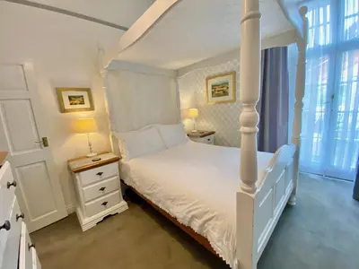 a bedroom with a white bed and two night stands at WE ARE UNIQUE ! 4 min walk to Beach, Pubs, Restaurants, Shops, Htd Pool, Hottub, Games rm, 1 acre Garden, BBQ's Coast to Coast cycle path, Beautiful, Bassets acre, Only six 1-3 bedroom SUPERB apartments, Free Parking and WIFI in Portreath