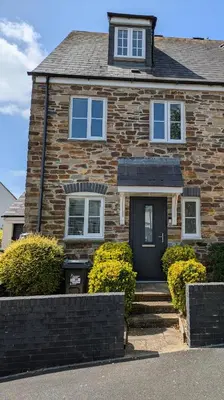 a brick house with a black door and bushes at Lanhydrock View in Bodmin