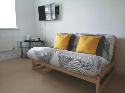 a couch with two yellow pillows in a living room at Lanhydrock View in Bodmin