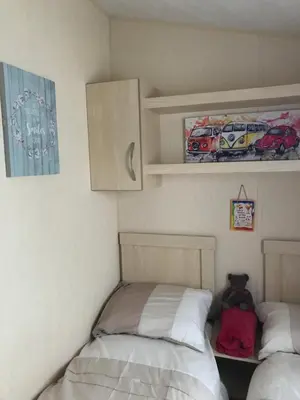 a bedroom with two beds and a cupboard at Take me to the beach at J&S caravan holidays Newquay Bay resort in Saint Columb Minor