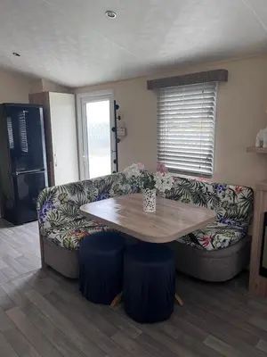a living room with a table and a couch at Take me to the beach at J&S caravan holidays Newquay Bay resort in Saint Columb Minor