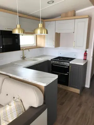 a kitchen with white cabinets and a black stove at Par Sands Coastal Holiday park in Par