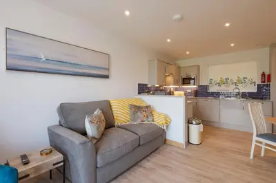 a living room with a couch and a kitchen at Porth Veor Manor Villas & Apartments in Newquay