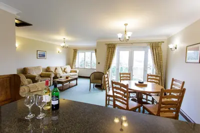a kitchen and living room with a table and wine glasses at Porth Veor Manor Villas & Apartments in Newquay