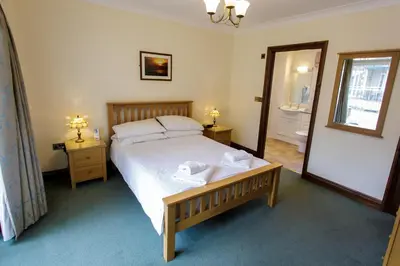a bedroom with a large bed and a mirror at Porth Veor Manor Villas & Apartments in Newquay