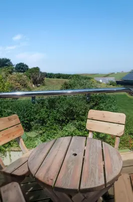 a wooden picnic table and chairs on a porch at Porth Veor Manor Villas & Apartments in Newquay