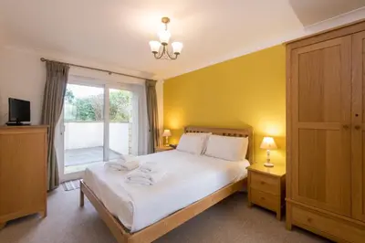 a bedroom with a bed with white sheets and a window at Porth Veor Manor Villas & Apartments in Newquay