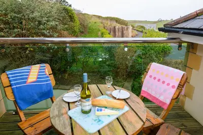 a wooden table with a bottle of wine and two chairs at Porth Veor Manor Villas & Apartments in Newquay