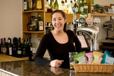 a woman sitting at a counter in a bar at Porth Veor Manor Villas & Apartments in Newquay