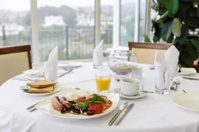 a table with a plate of food and a glass of orange juice at Porth Veor Manor Villas & Apartments in Newquay