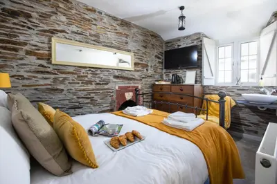 a bedroom with a large bed with a brick wall at The Olde Malthouse Inn in Tintagel