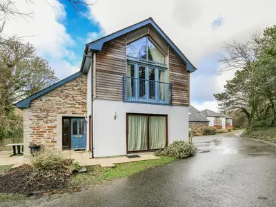 a brick house with a blue balcony on a street at Holiday Home Haven by Interhome in Perranwell