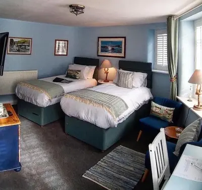 a hotel room with two beds and a couch at Bridge House Bed & Breakfast in Boscastle