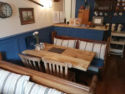 a wooden table and chairs in a restaurant at Bridge House Bed & Breakfast in Boscastle