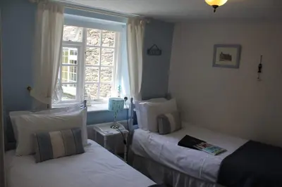 a bedroom with two beds and a window at Bridge House Bed & Breakfast in Boscastle