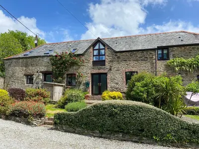 a stone house with a landscaping in front of it at Haybarn in Fowey