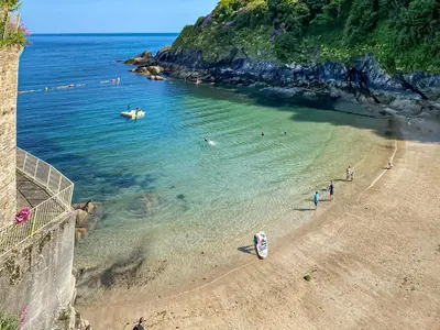 a beach with a group of people in the water at Haybarn in Fowey