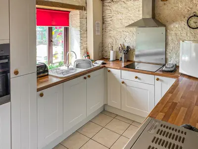 a kitchen with white cabinets and a sink at Haybarn in Fowey
