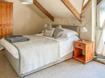 a bedroom with a large bed and a wooden table at Haybarn in Fowey