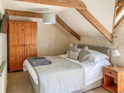 a bedroom with a white bed and a wooden cabinet at Haybarn in Fowey