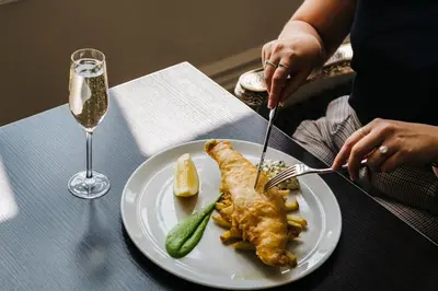 a person eating fish and a pickle on a plate at The Alverton in Truro