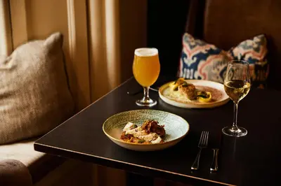 a table with two plates of food and two glasses of wine at The Alverton in Truro