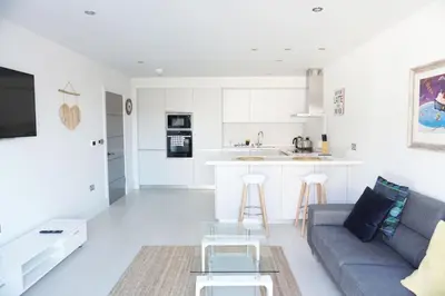 a living room with a couch and a kitchen at Saltwater Suites at Fistral in Newquay