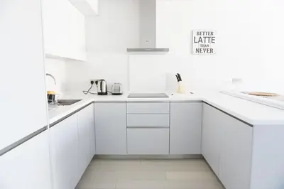 a white kitchen with white cabinets and a sink at Saltwater Suites at Fistral in Newquay