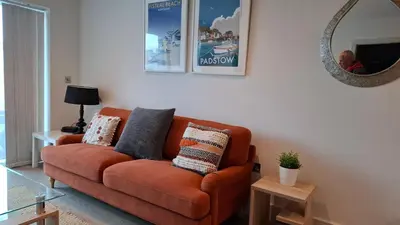 an orange couch in a living room with a mirror at Saltwater Suites at Fistral in Newquay