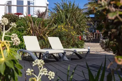 two white chairs sitting on a patio with plants at Chelsea House Holiday Apartments in Falmouth