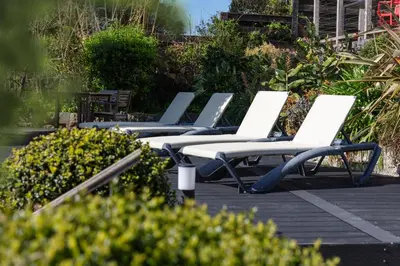 a row of white lounge chairs on a deck at Chelsea House Holiday Apartments in Falmouth