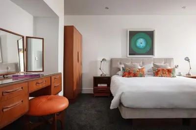 a bedroom with a bed and a vanity and a mirror at Chelsea House Holiday Apartments in Falmouth