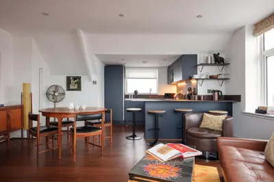 a living room with a table and a kitchen at Chelsea House Holiday Apartments in Falmouth