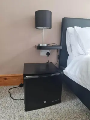 a bed with a black nightstand with a lamp on it at Tippy's Guesthouse in Newquay