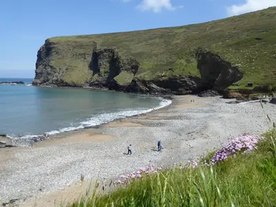 two people walking on a beach near the ocean at Lower Tresmorn Farmhouse in Crackington Haven