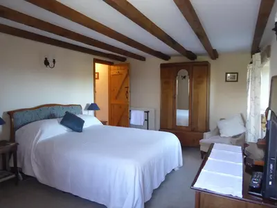 a bedroom with a white bed and a couch at Lower Tresmorn Farmhouse in Crackington Haven