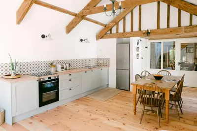 a kitchen with white cabinets and a wooden table at Lower Tresmorn Farmhouse in Crackington Haven