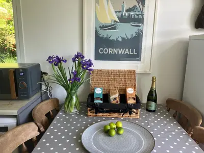 a dining room table with a bottle of wine and grapes at Fuchsia Cottage in Porthallow