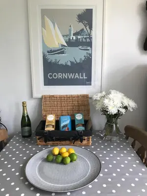 a table with a basket of food and a plate of fruit at Fuchsia Cottage in Porthallow