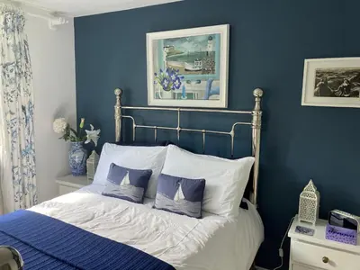 a bedroom with blue walls and a bed with pillows at Fuchsia Cottage in Porthallow