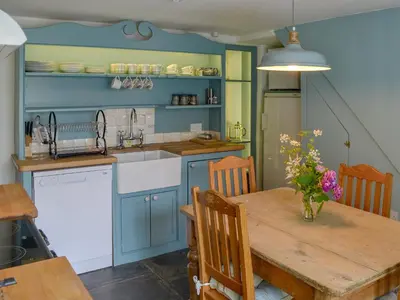 a kitchen with blue cabinets and a wooden table at Sunnyside in Delabole