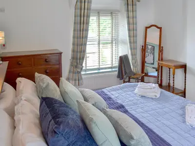 a bedroom with a bed and a dresser and a mirror at Sunnyside in Delabole