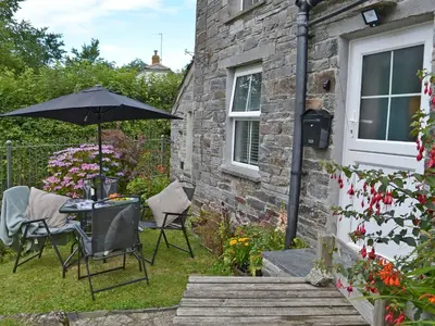 a table and chairs with an umbrella in a garden at Sunnyside in Delabole