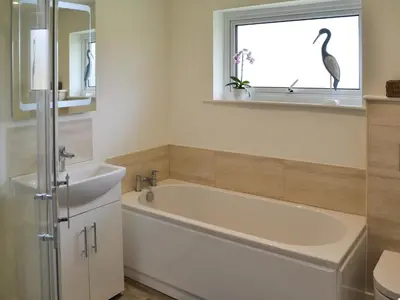 a bathroom with a tub and a bird in a window at Moonraker in Port Isaac