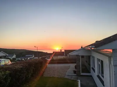 a sunset over a house with the sun setting at Moonraker in Port Isaac