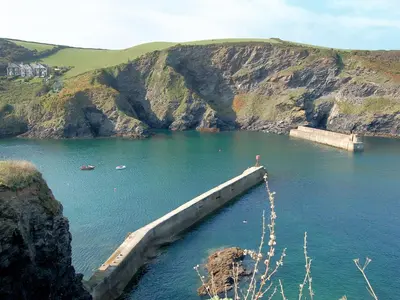 a barge in a body of water next to a mountain at Moonraker in Port Isaac