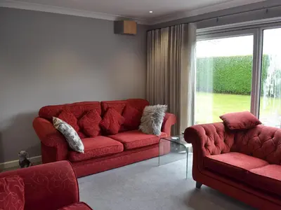 a living room with two red couches and a window at Heatherstone in Illogan