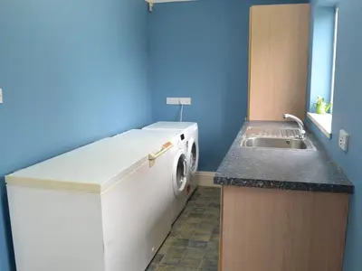 a small kitchen with a washing machine and a sink at Heatherstone in Illogan